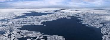 A professional photo of melting Arctic sea ice under dramatic skies, with cracks spreading across the frozen surface