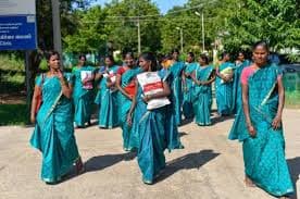 A realistic newsroom photo of ASHA and anganwadi workers at a village health and nutrition day—women in saris