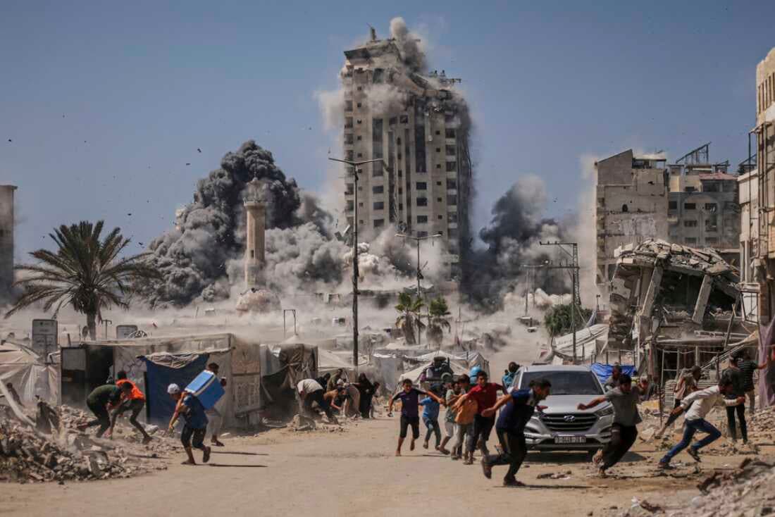Civilians flee as buildings collapse during Israeli airstrikes in Gaza, with smoke and debris filling the city skyline.