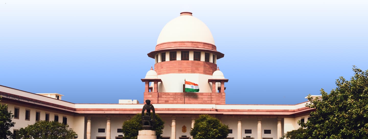 The Supreme Court of India building in New Delhi, featuring its iconic dome, the national flag flying at the centre.