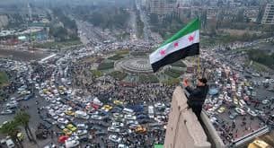 Crowds outside a polling station in Damascus under security watch, with Syrian flags fluttering
