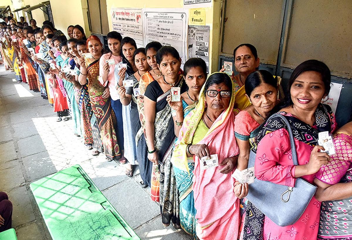 Women voters in Maharashtra standing in a queue holding their voter ID cards during local body elections.