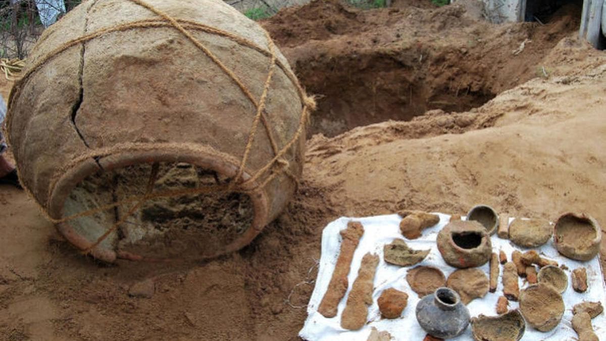 A wide shot of an open trench at Thirumalapuram showing a rectangular stone-slab chamber with urns in situ